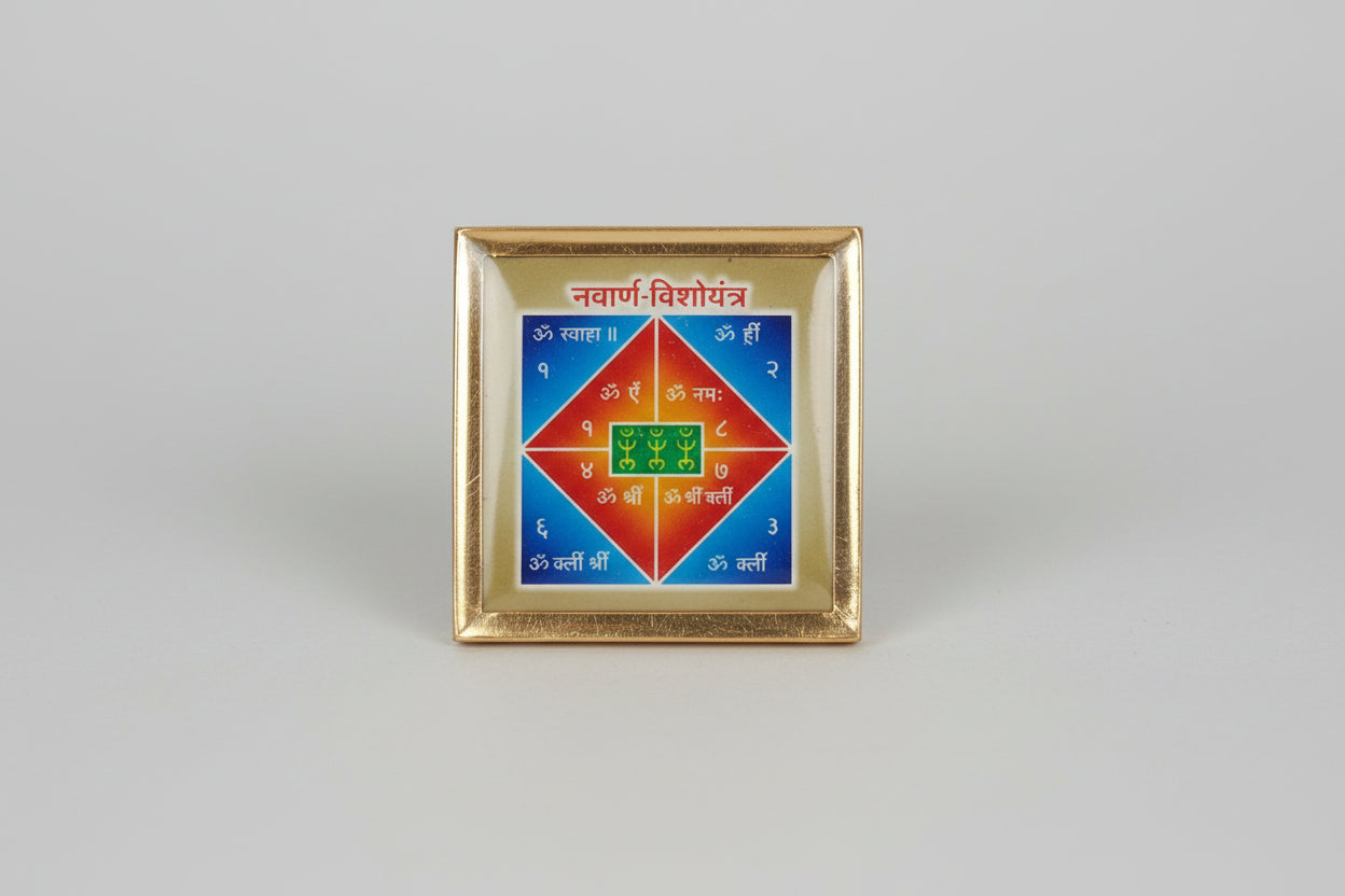 A yantra, which is a geometric spiritual artwork, predominantly in green and orange colors, held between fingers.