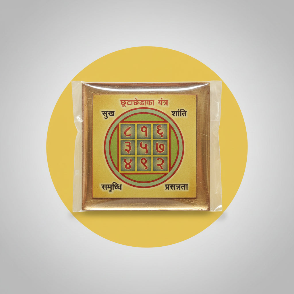 A hand holding a Chutta Cheda Yantra, which is a colorful geometric pattern on a square surface, primarily in orange, with numerical values and Sanskrit text.