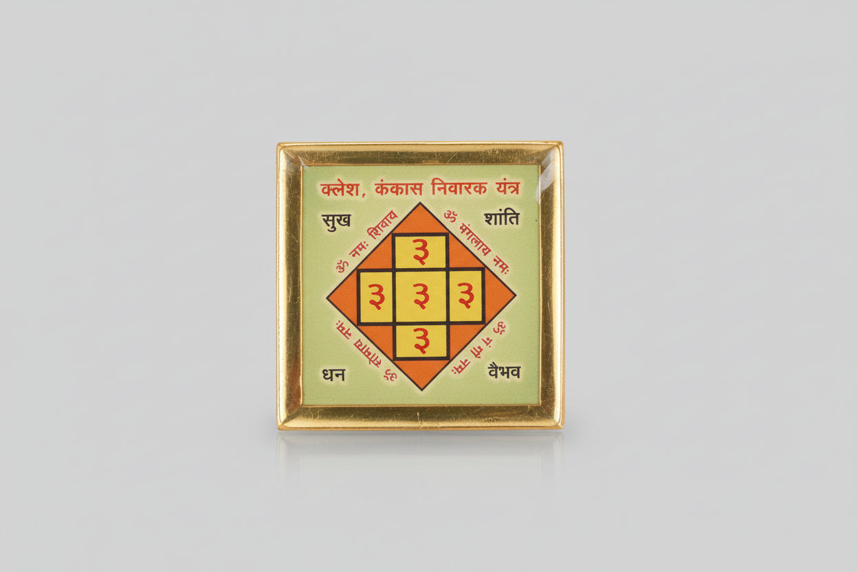 A hand holding a small, square-shaped yantra with geometric patterns and Devanagari script on it.
