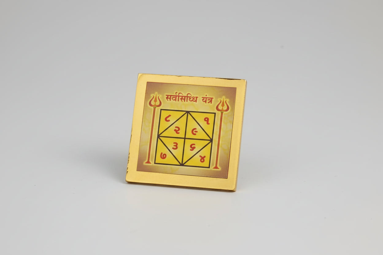 A hand holding a Sarv Siddh yantra, which is a square-shaped talisman with geometric patterns and sacred numerals in a glowing frame.