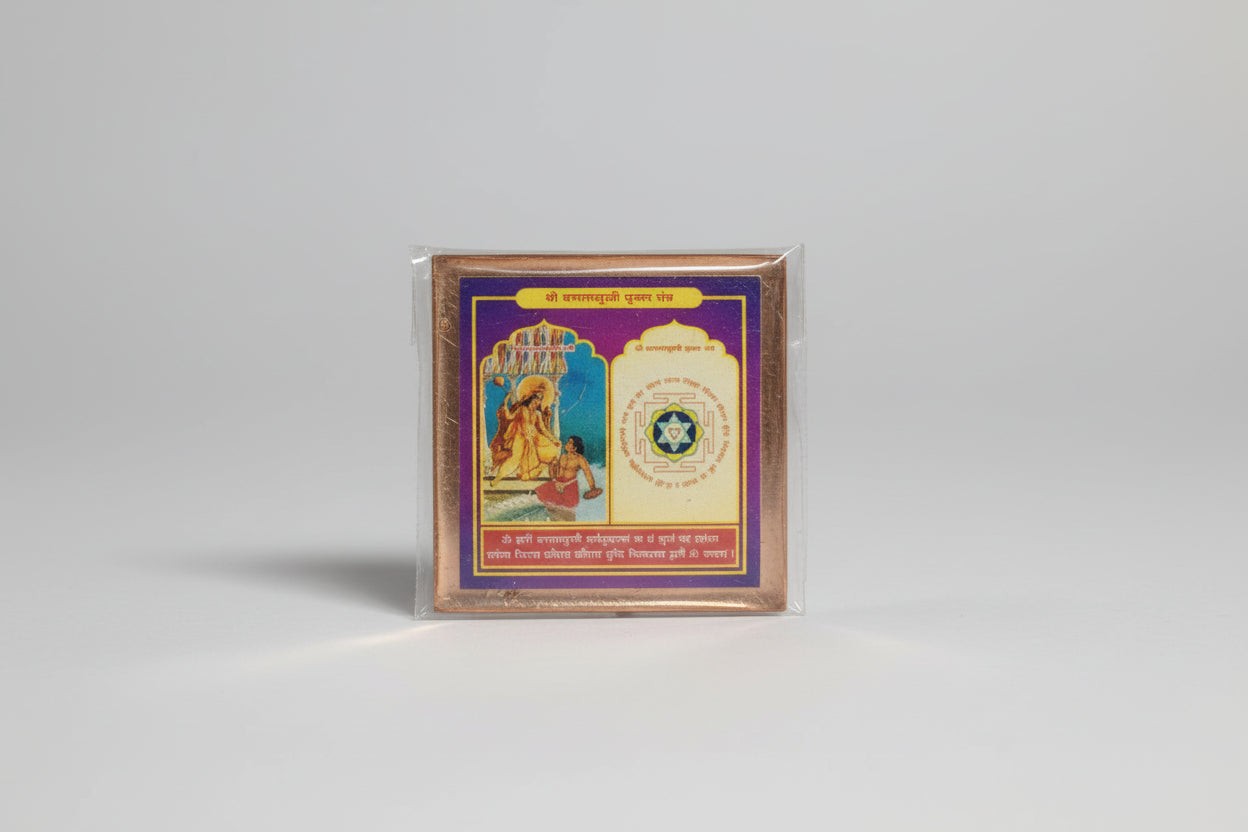 A hand holding a packaged Shri Baglamukhi Yantra with a colorful image and text on it.
