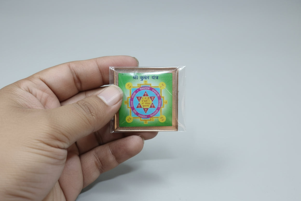 A hand holding a Shri Kuber Yantra, a colorful geometric pattern on a square piece of paper, commonly used as a Hindu spiritual remedy for wealth and prosperity.
