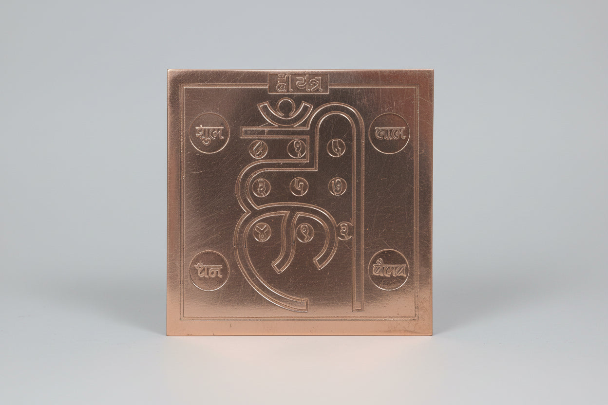 A copper-colored metal yantra with engraved symbols, typically used as a spiritual or sacred tool in Hinduism.