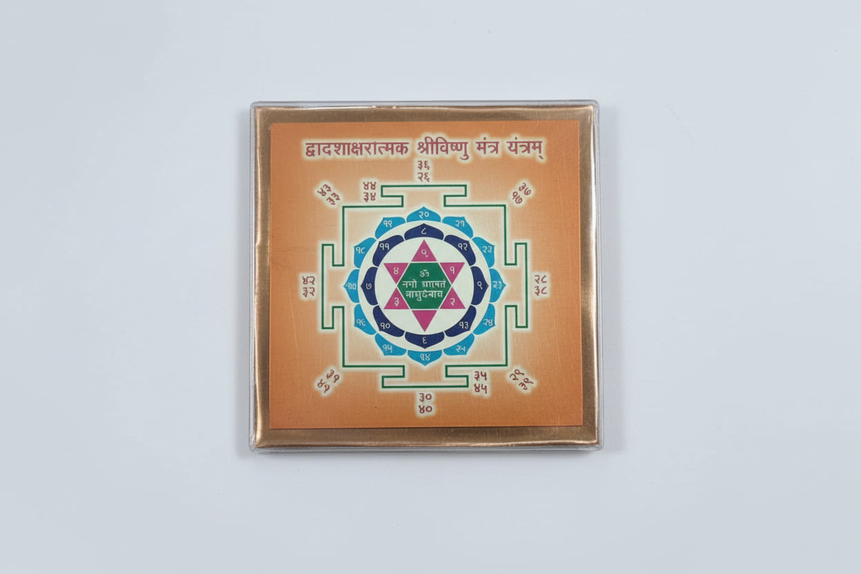 A colorful Shri Krishna Yantra, a sacred geometric diagram, displayed within a glass case.