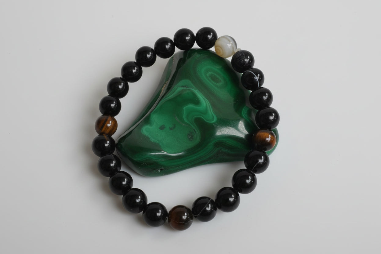 A Sulemani Hakik bracelet with black and green beads, displayed on a white surface, with a price tag and contact information for the seller.