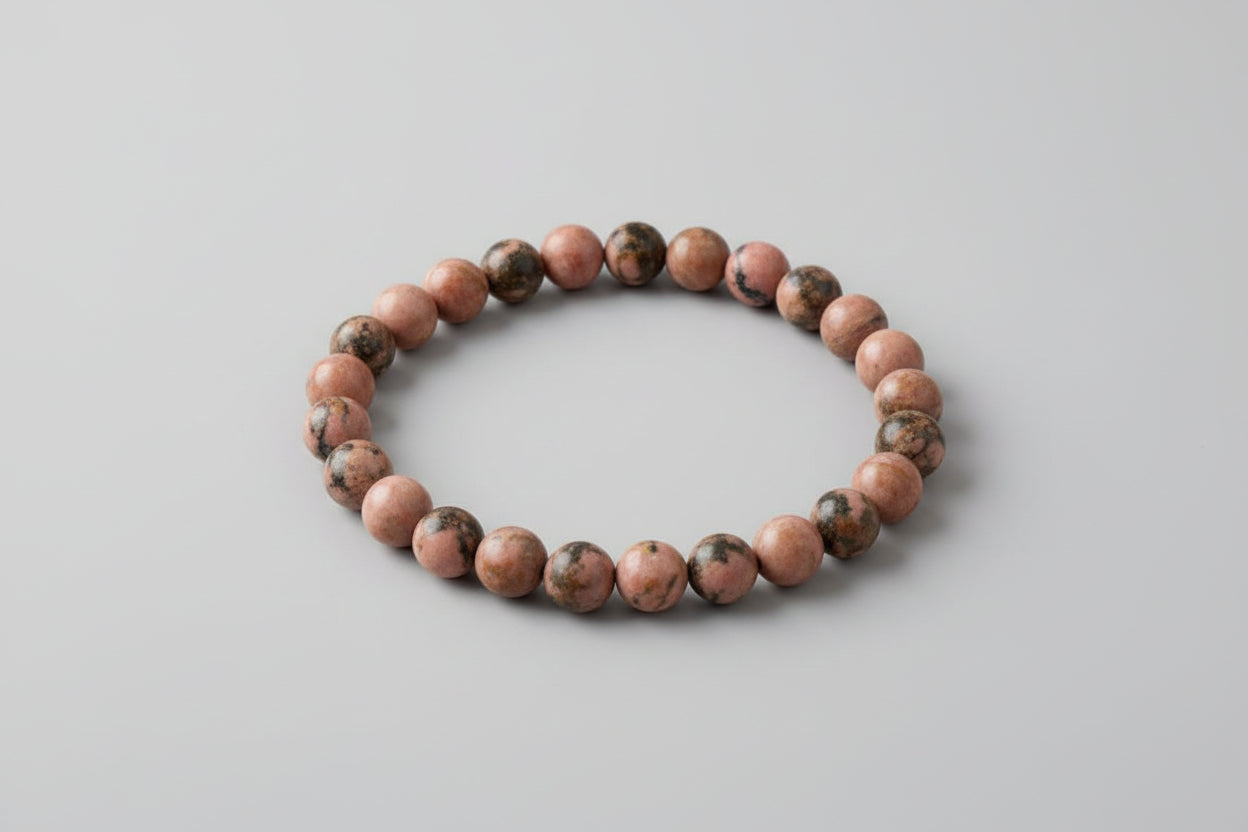 A Rhodonite bracelet displayed on a white surface, with the bracelet's name, price, and contact information provided.