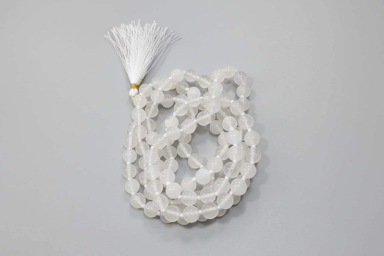 A white moonstone Japmala with a decorative tassel, intended for prayer or spiritual use.