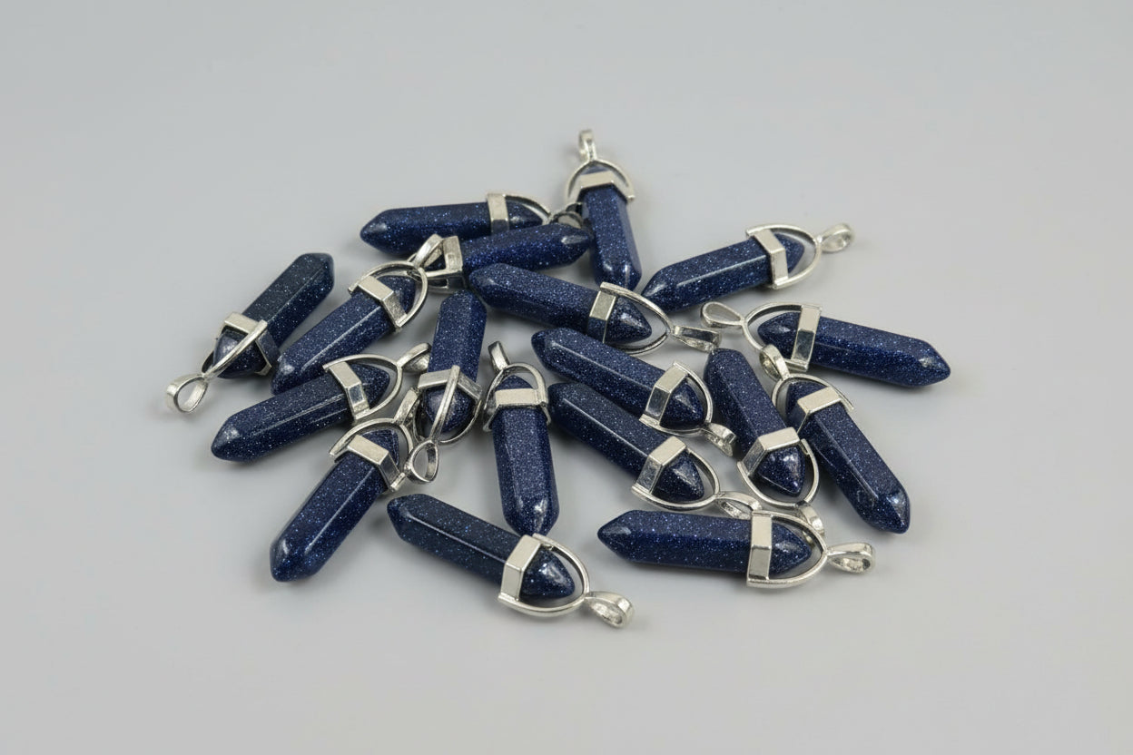 A collection of blue sunstone pencil pendants with metal caps at each end, displayed on a textured brown surface.