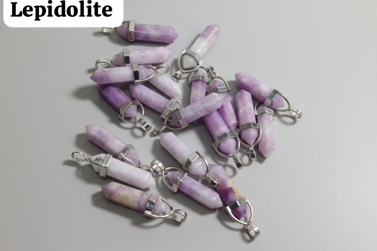 A collection of Lepidolite pencil pendant necklaces displayed on a textured surface.