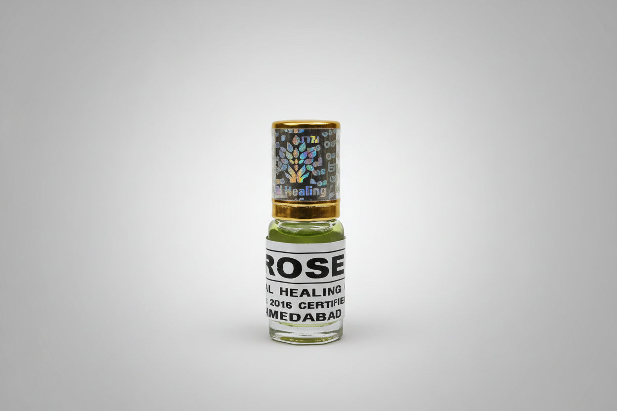 A small bottle labeled 'Natural Rose Attar' on a wooden surface.