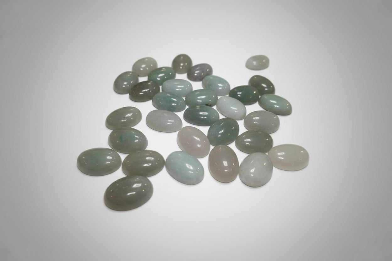 A collection of green aventurine stones of various shades and sizes, displayed on a red surface.