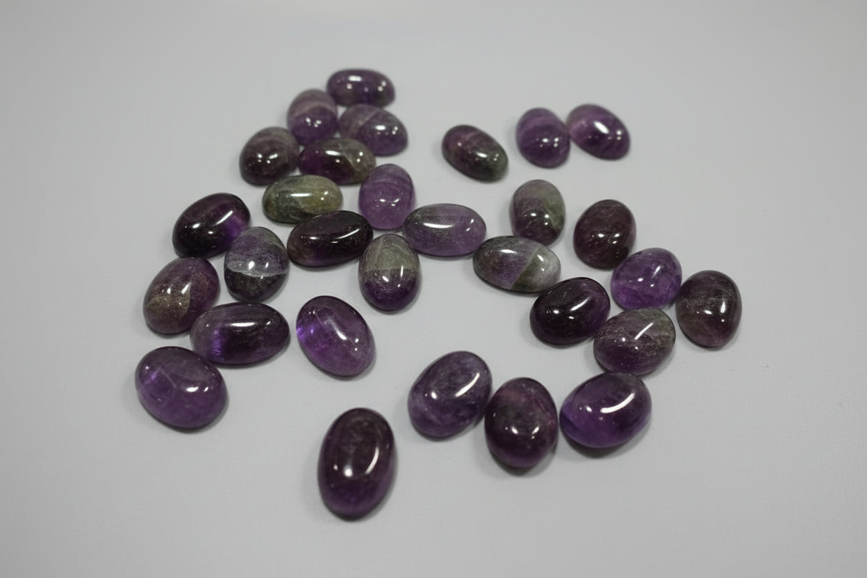 A collection of polished amethyst stones displayed on a red surface.