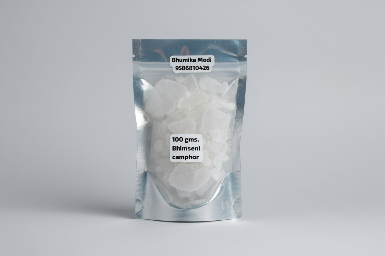 A sealed, transparent plastic pouch containing 100 grams of Bhimseni camphor with a label displaying the weight and contact information.