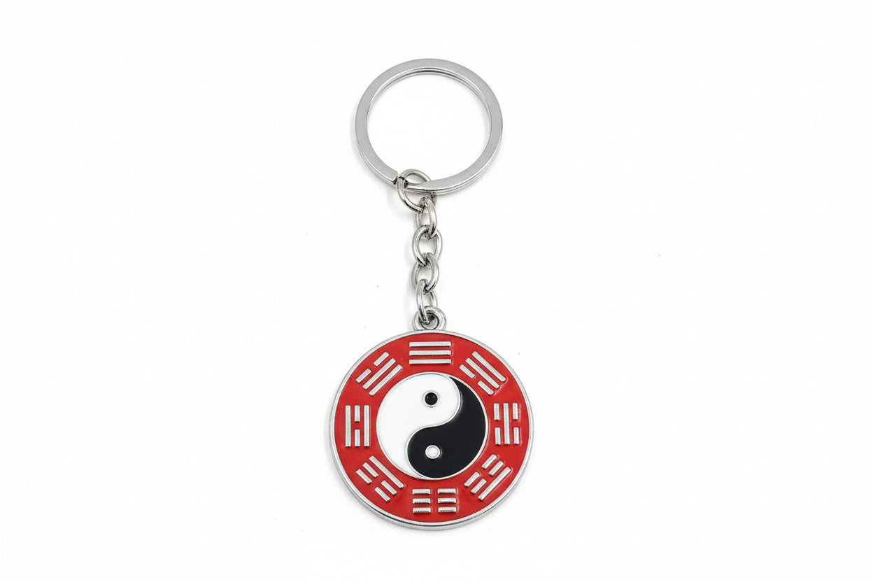 A keychain featuring a yin yang symbol with a red and black design on a metal ring.