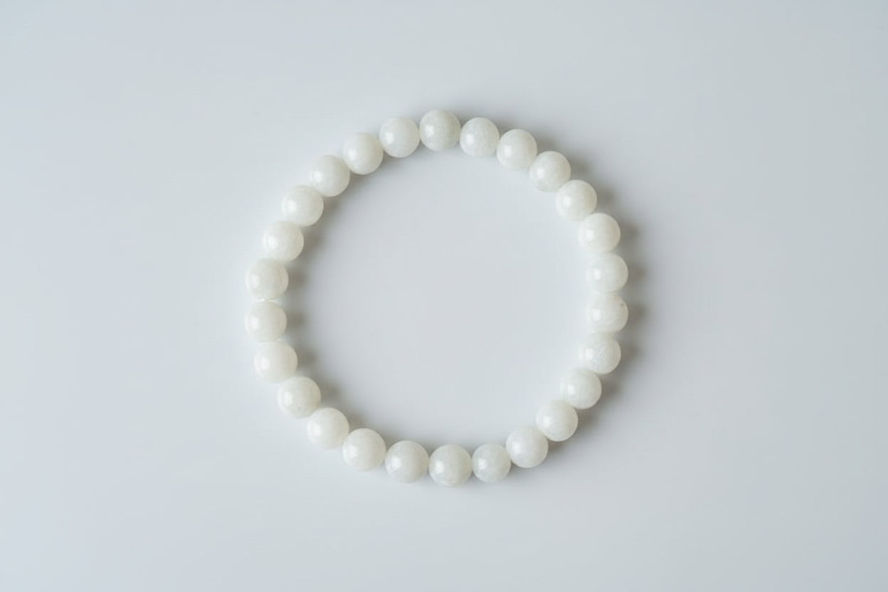 A Moonstone bracelet displayed on a paper with floral elements in the background, alongside text detailing the bracelet's benefits and contact information.