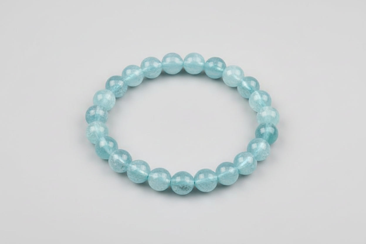 A bracelet made of round Aquamarine stones displayed on a soft, white surface with the text 'Aquamarine bracelet AAA Quality $1500' overlaid.