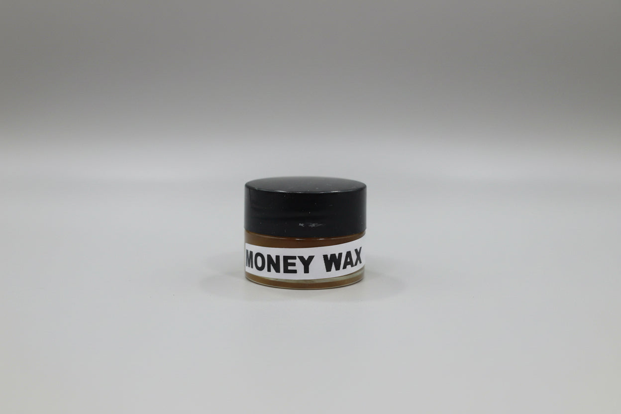 Small container labeled 'Money Wax' on a red surface