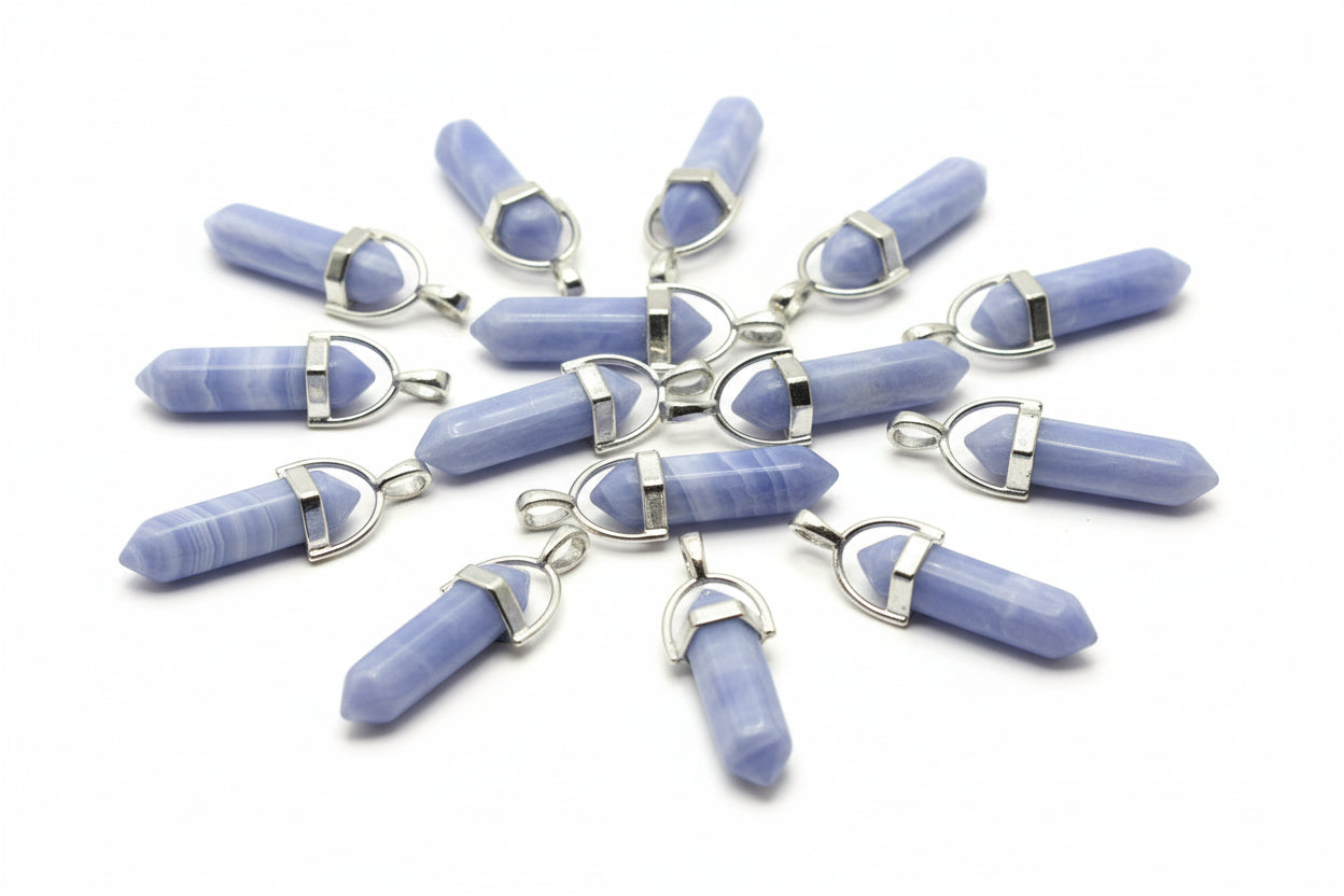 A collection of blue lace agate pencil-shaped pendants with metal caps at both ends and a loop for attachment, displayed on a brown surface.