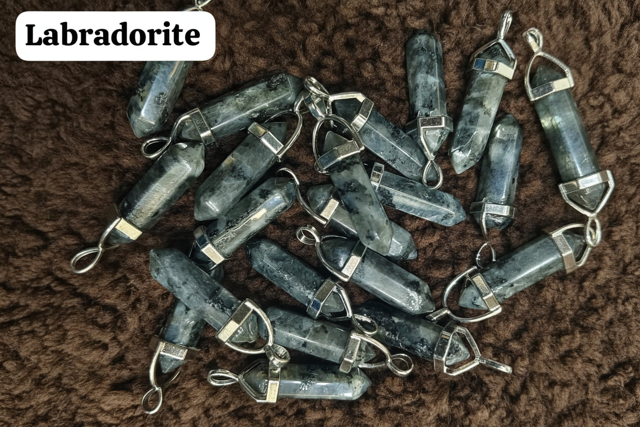 A collection of labradorite pencil pendants with metal clasps, displayed on a textured brown surface.