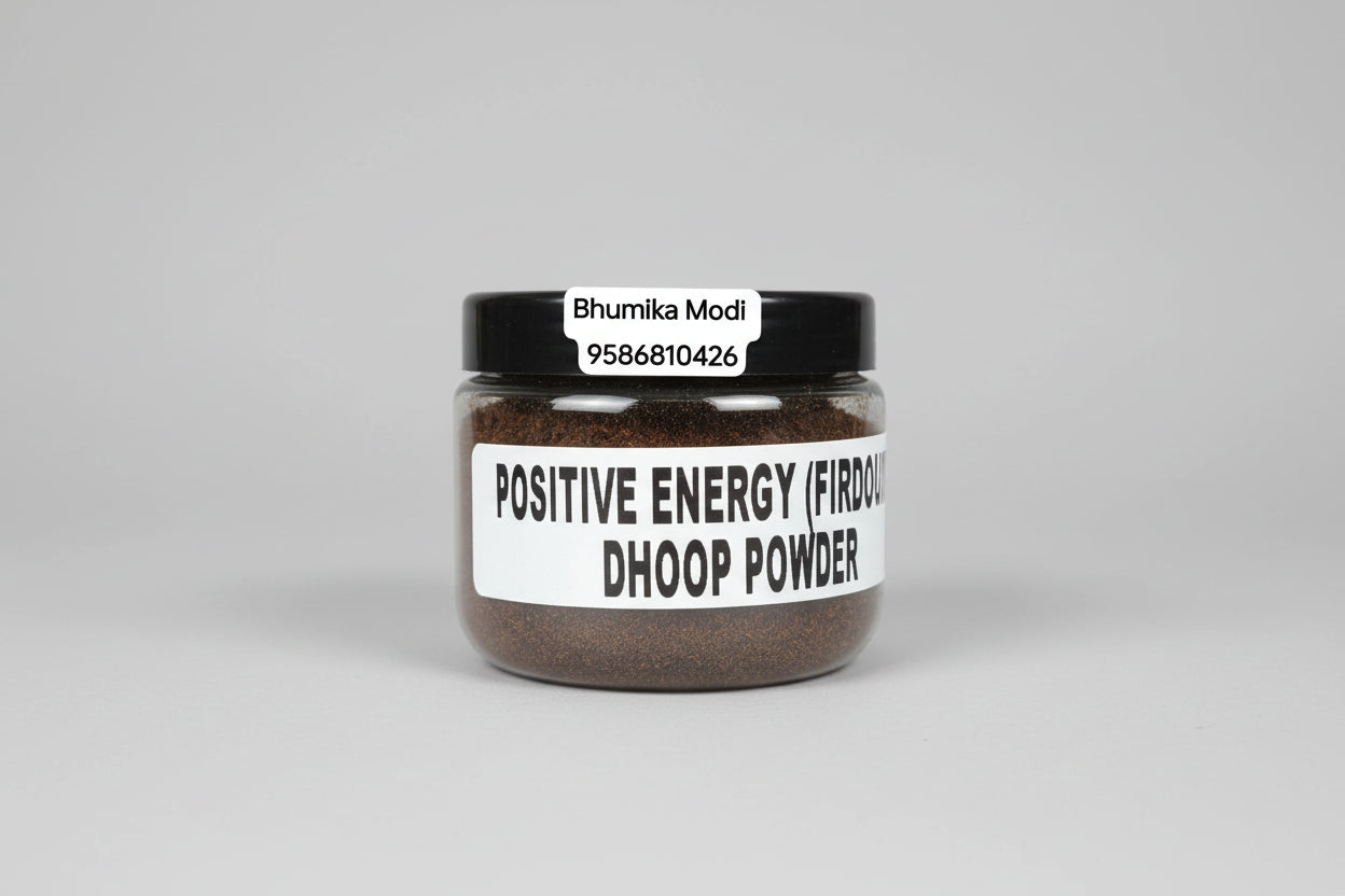 A container labeled 'POSITIVE ENERGY (FIRDOUS) DHOOP POWDER' held in a person's hand against a red background.