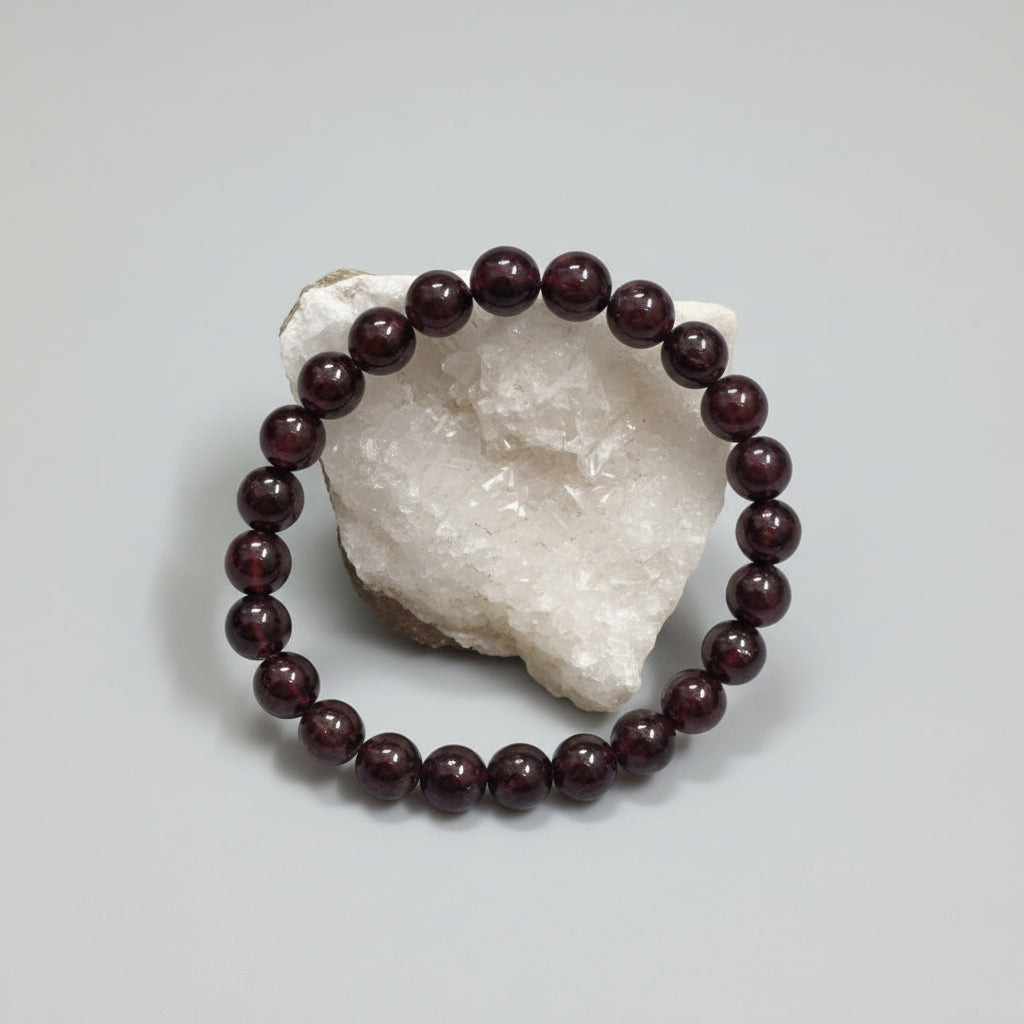 A Garnet bracelet displayed on a white rock, with the bracelet's name and price ('$750/-') mentioned.