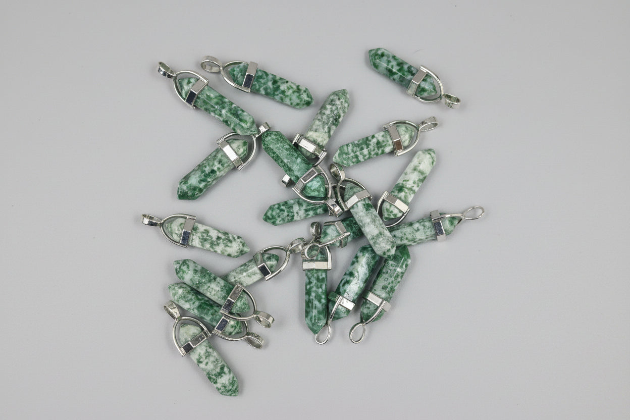A collection of Tree Agate pencil pendants displayed on a textured surface.